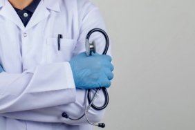 Doctor crossing arms while holding stethoscope in white coat front view.